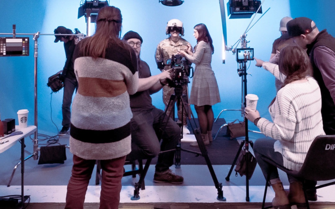 A film crew setting up cameras in a studio with blue background