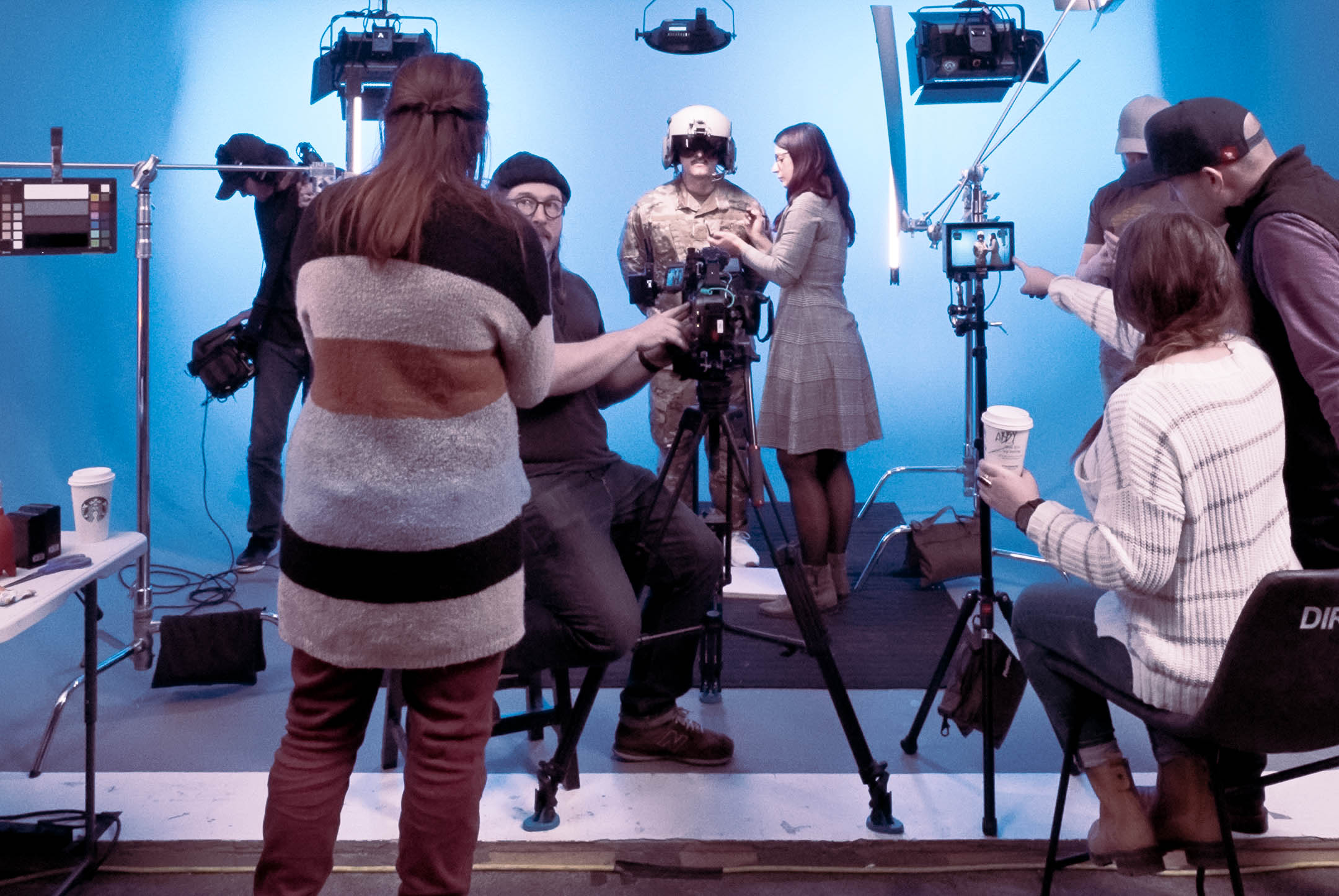 A film crew setting up cameras in a studio with blue background