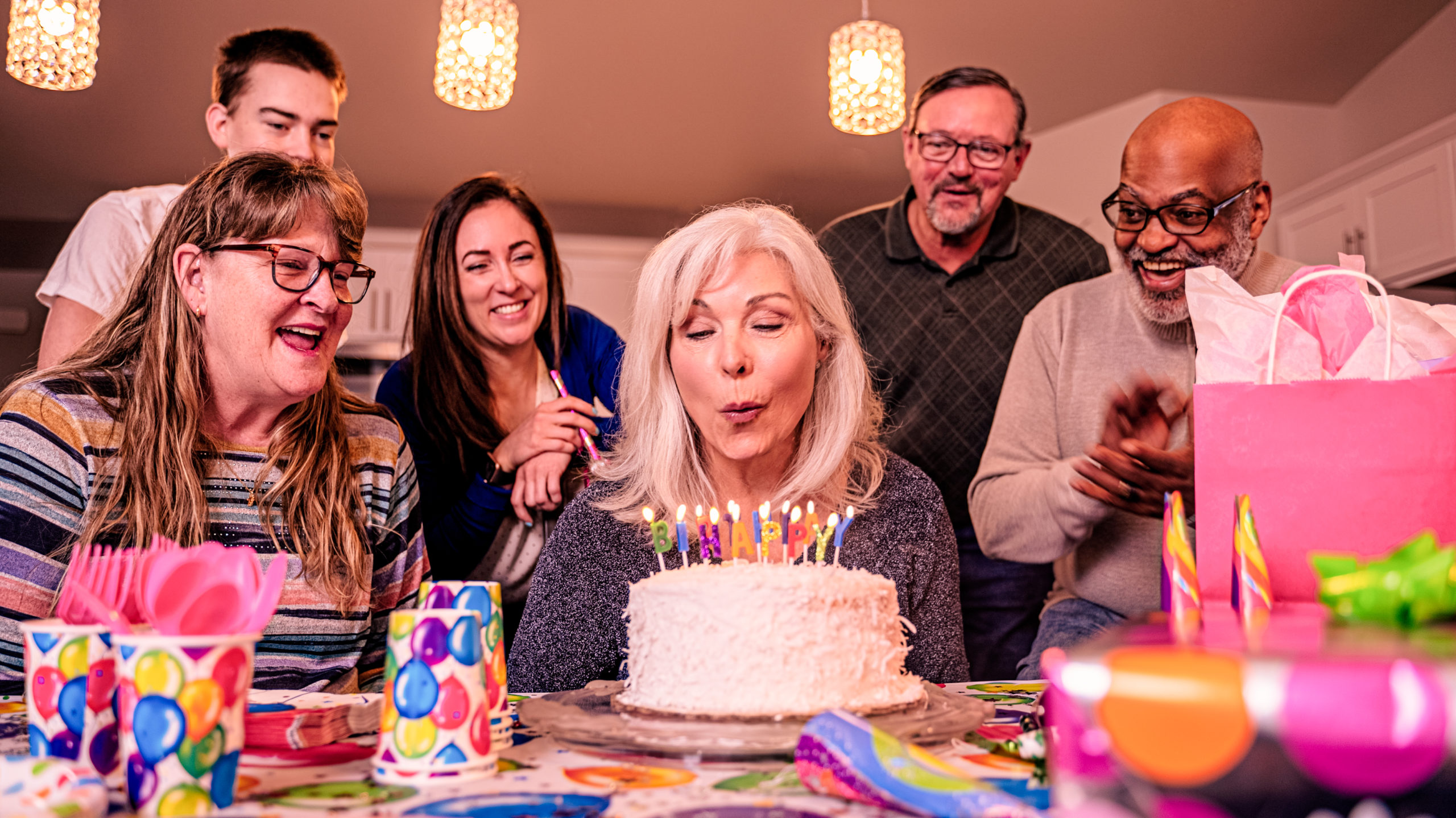 A grandma blowing out candles on her birthday with family