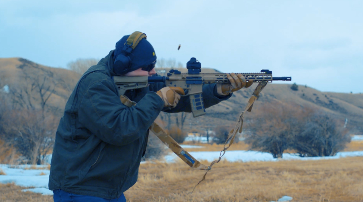 Man standing shooting gun in snowy field